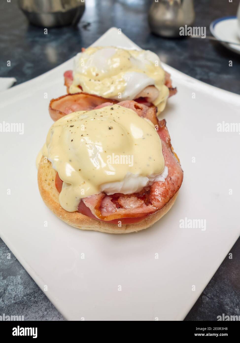 Huevos beicon canadiense Benedict huevo escalfado y tomate en un muffin inglés con salsa hollandaise Foto de stock