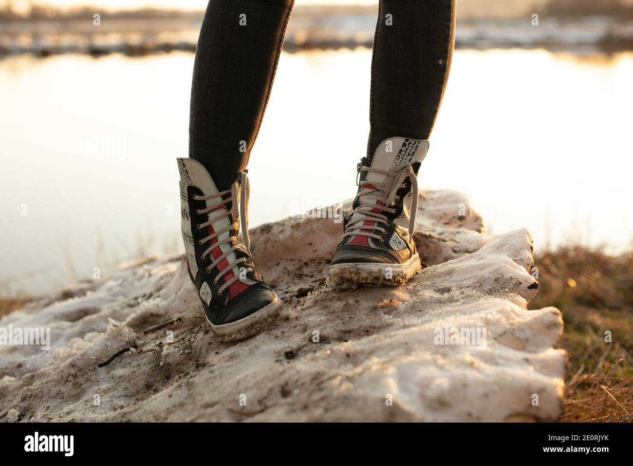 Zapatillas de lona de moda para mujer de alta piel brillante y botas de  goma blanca con jeans y ambos pies hacia delante Fotografía de stock - Alamy