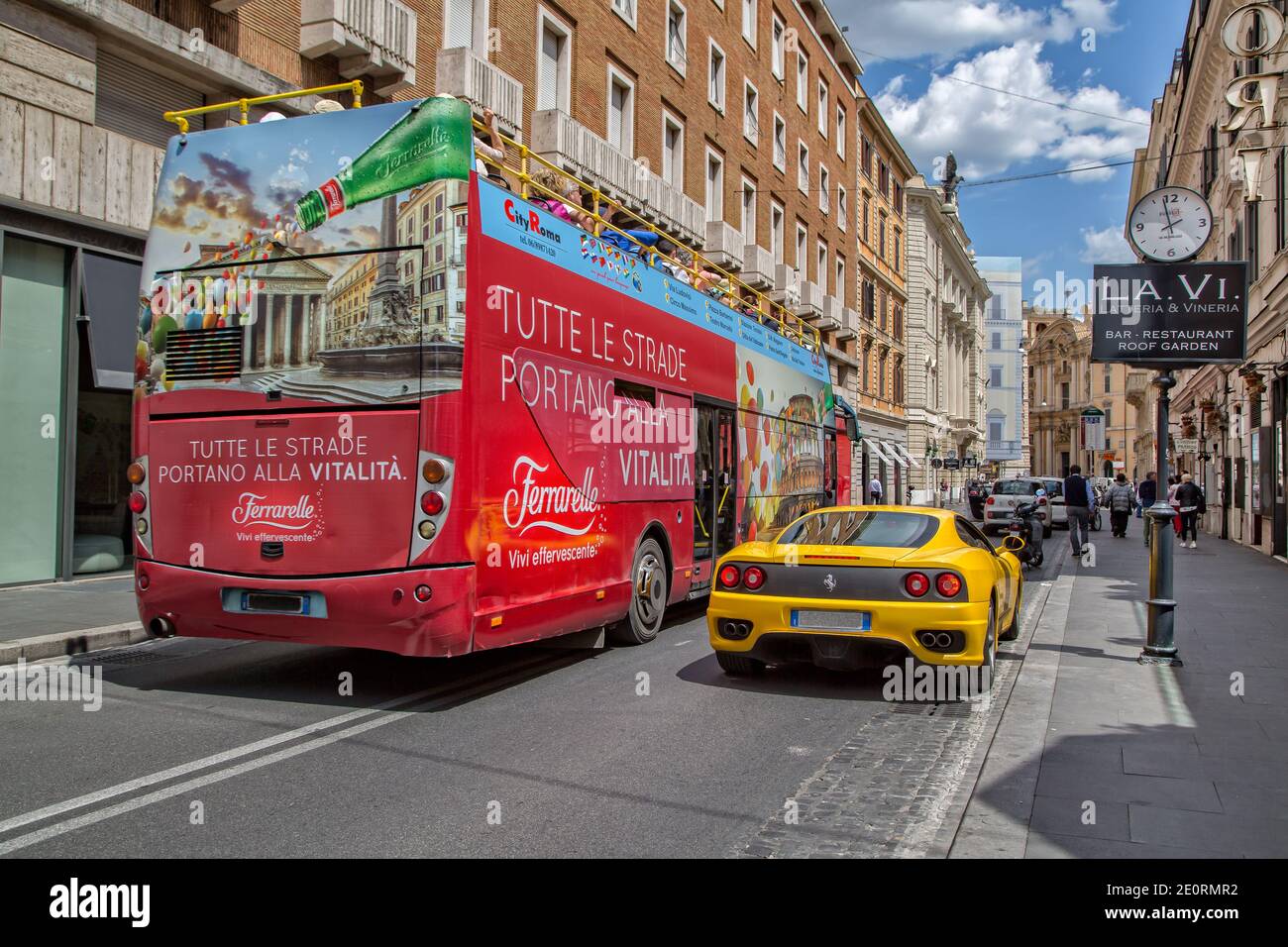 Visita turística en autobús de la ciudad en un hermoso día de verano en Roma. Autobús turístico rojo y amarillo Ferrari 360 lado a lado en una calle muy transitada de Roma, Italia Foto de stock