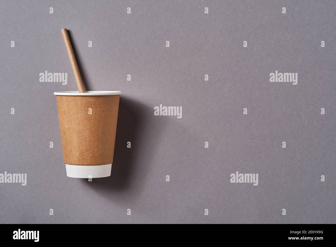 Taza de café para llevar marrón con papel de paja potable sobre fondo de color gris tendencia. Cero desperdicio, concepto de estilo de vida sostenible. Vista superior Foto de stock
