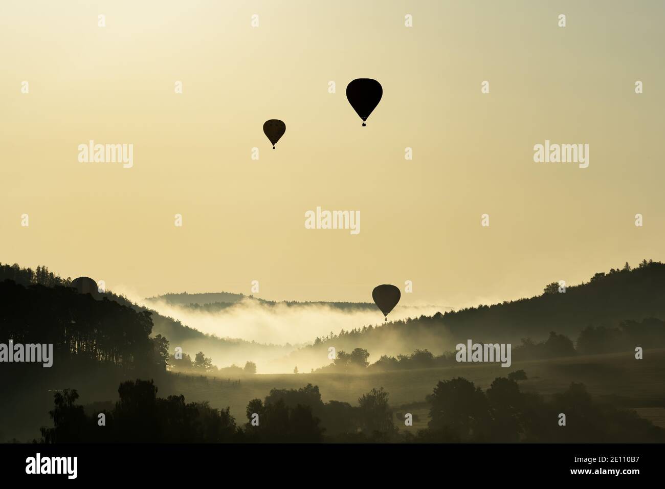 Globos de aire caliente flotando en la luz de la mañana sobre el Paisaje de la República Checa Foto de stock