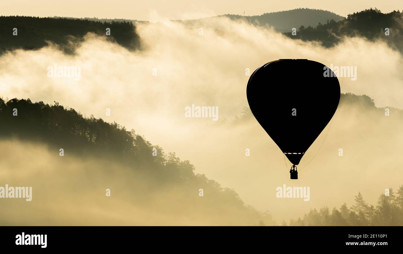 Globo de aire caliente flotando en la luz de la mañana sobre el Paisaje de la República Checa Foto de stock