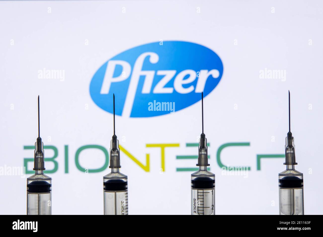Katmandú, Nepal - Enero 03 2021: Cierre de una jeringa contra el logo de Pfizer BioNTech Foto de stock