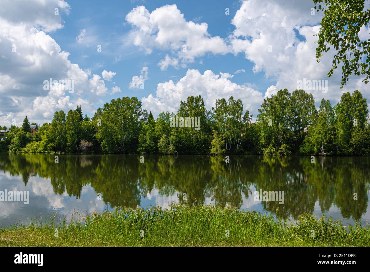 Reflejo de árboles verdes y cielo azul con nubes en espejo de la superficie del lago Foto de stock