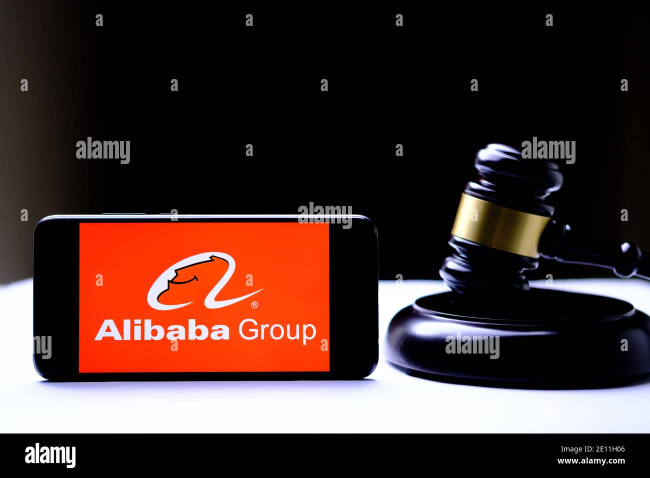 Stafford, Reino Unido - 3 de enero de 2021: Logotipo de Alibaba en el teléfono inteligente colocado junto a los jueces gavel. Concepto de regulación. Foto real, no una monta Foto de stock