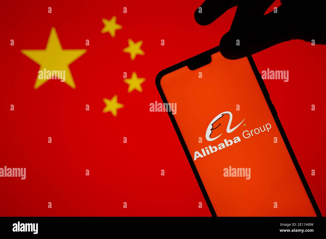 Stafford, Reino Unido - 3 de enero de 2021: Logotipo de Alibaba en una silueta de smartphone que se sostiene en el borde. Concepto para la investigación gubernamental Foto de stock