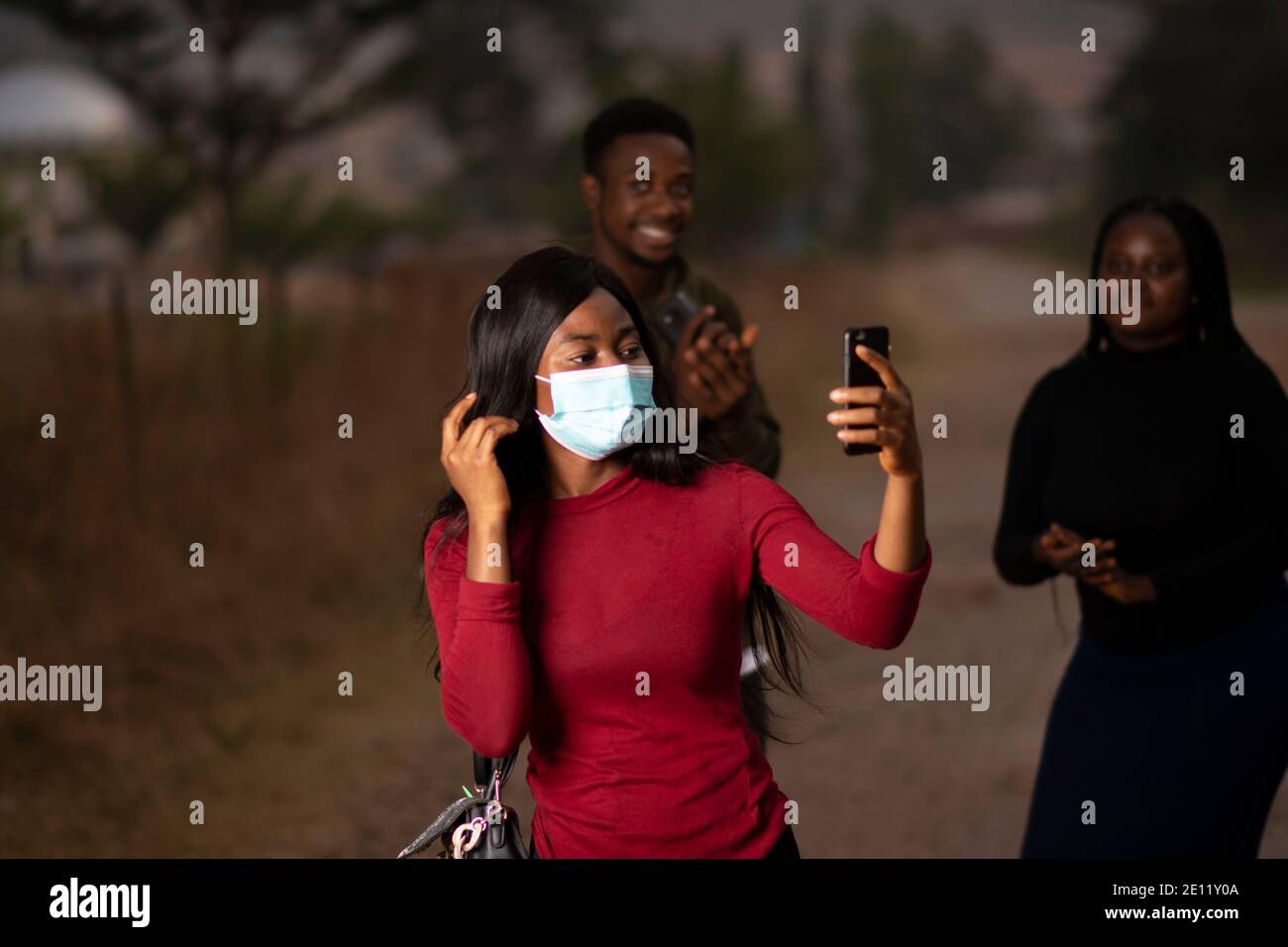 una mujer africana con una máscara y tomando un selfie Foto de stock
