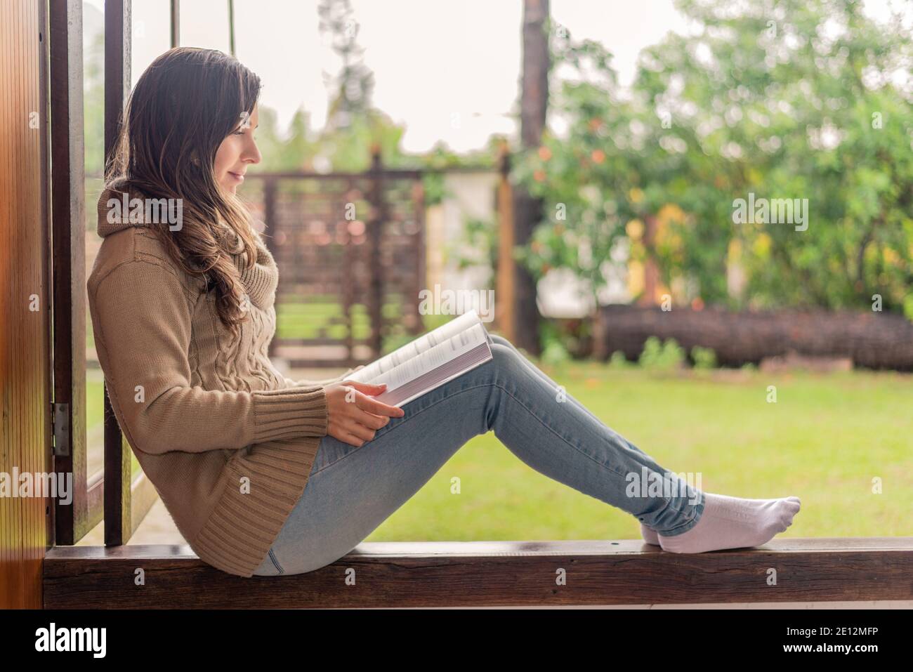 Mujer leyendo en la ventana por la mañana Foto de stock