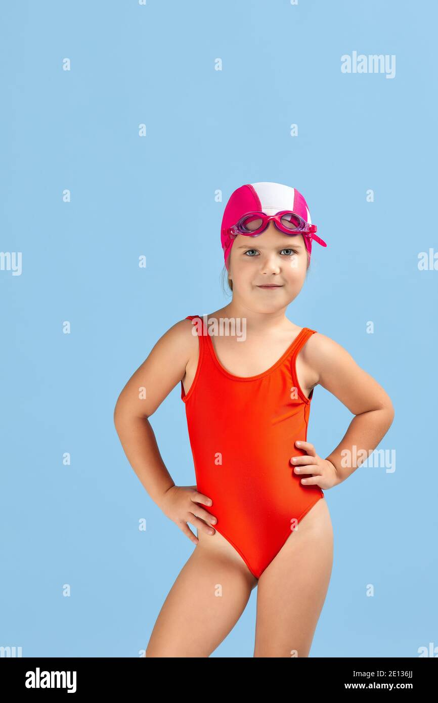 niña pequeña en traje de baño, gafas de natación y gorro de baño sobre fondo azul Fotografía de - Alamy