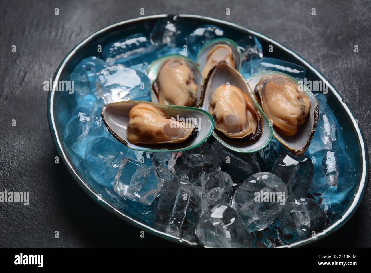 Mariscos mejillones crudos en un plato sobre cubitos de hielo Foto de stock