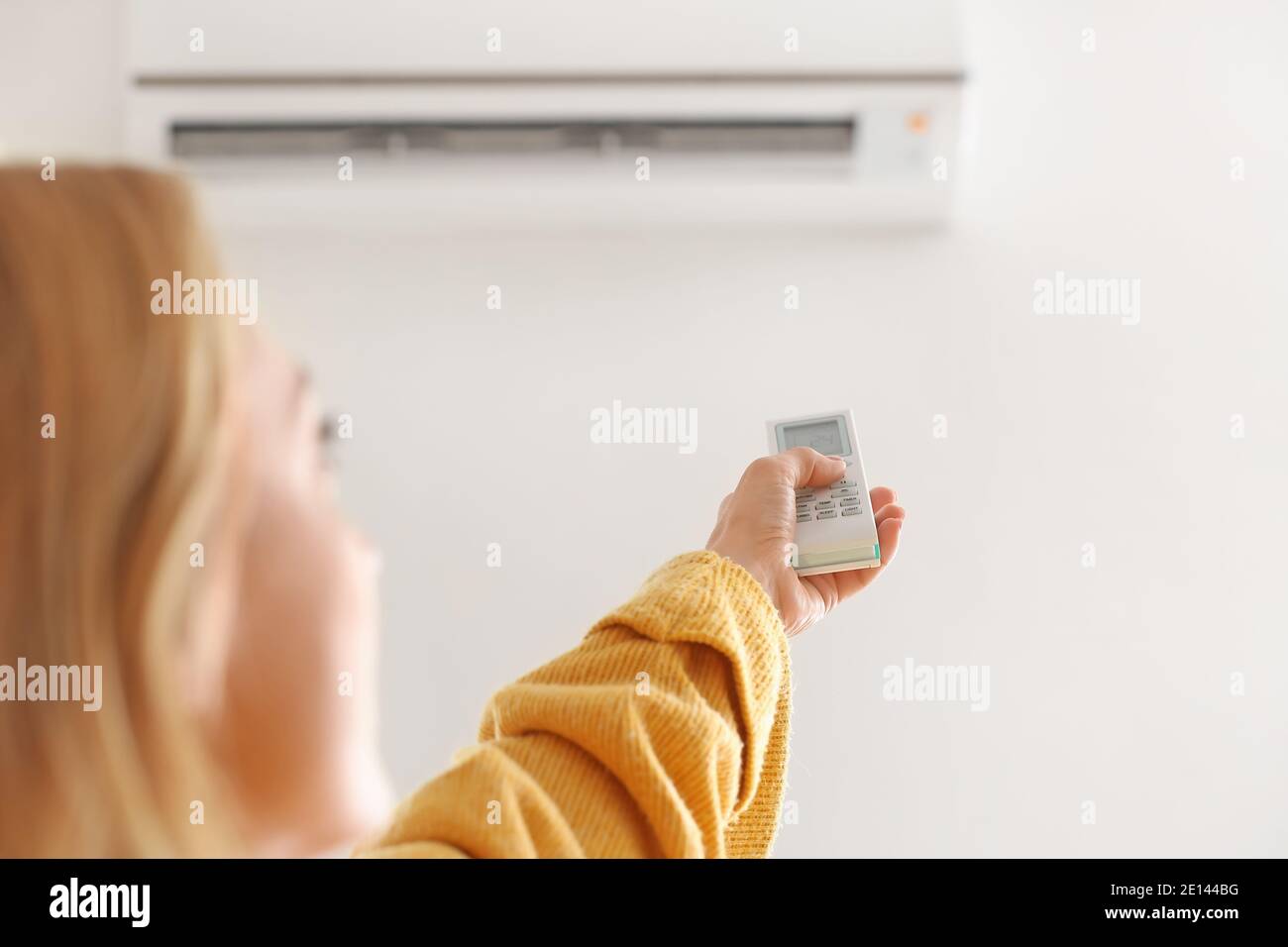 Mujer poniendo el aire acondicionado para calentar en casa. Concepto de  temporada de calefacción Fotografía de stock - Alamy