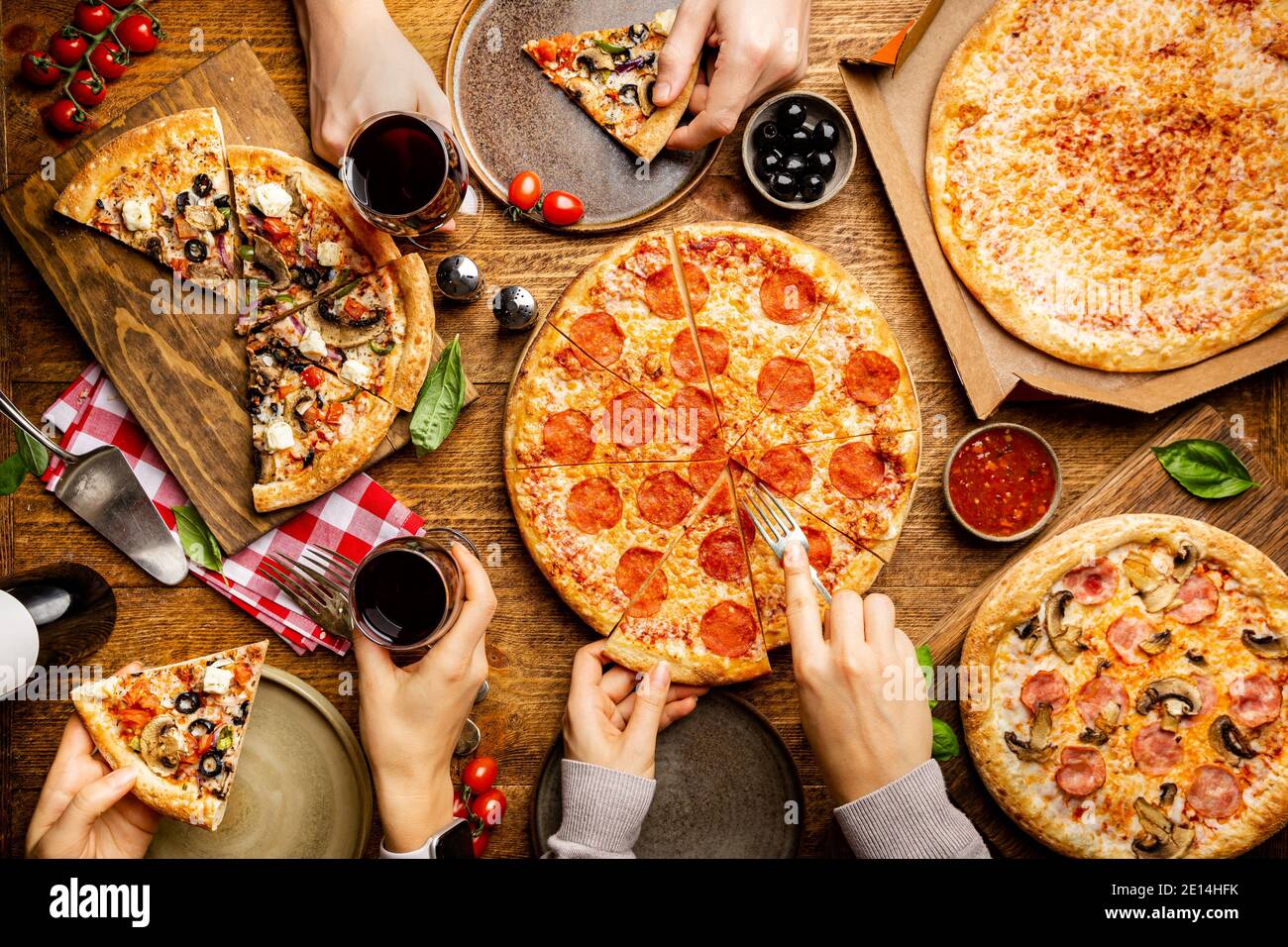 Familia o amigos fiesta de pizza. Gente que come diferentes tipos de pizza  y bebe vino tinto sobre una mesa de madera rústica, vista superior  Fotografía de stock - Alamy