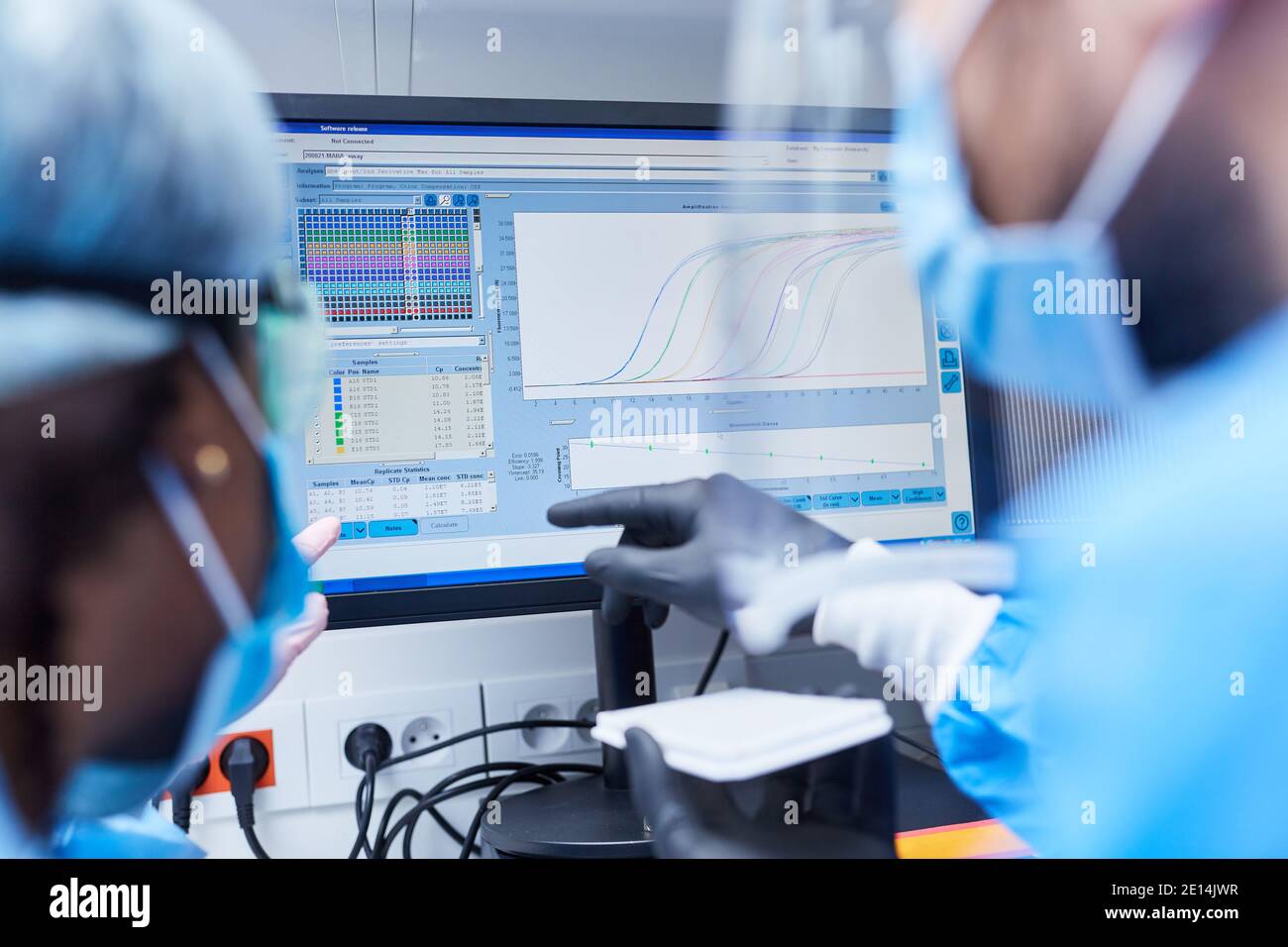 Dos investigadores en el análisis de datos de un experimento en el laboratorio en el monitor del ordenador Foto de stock