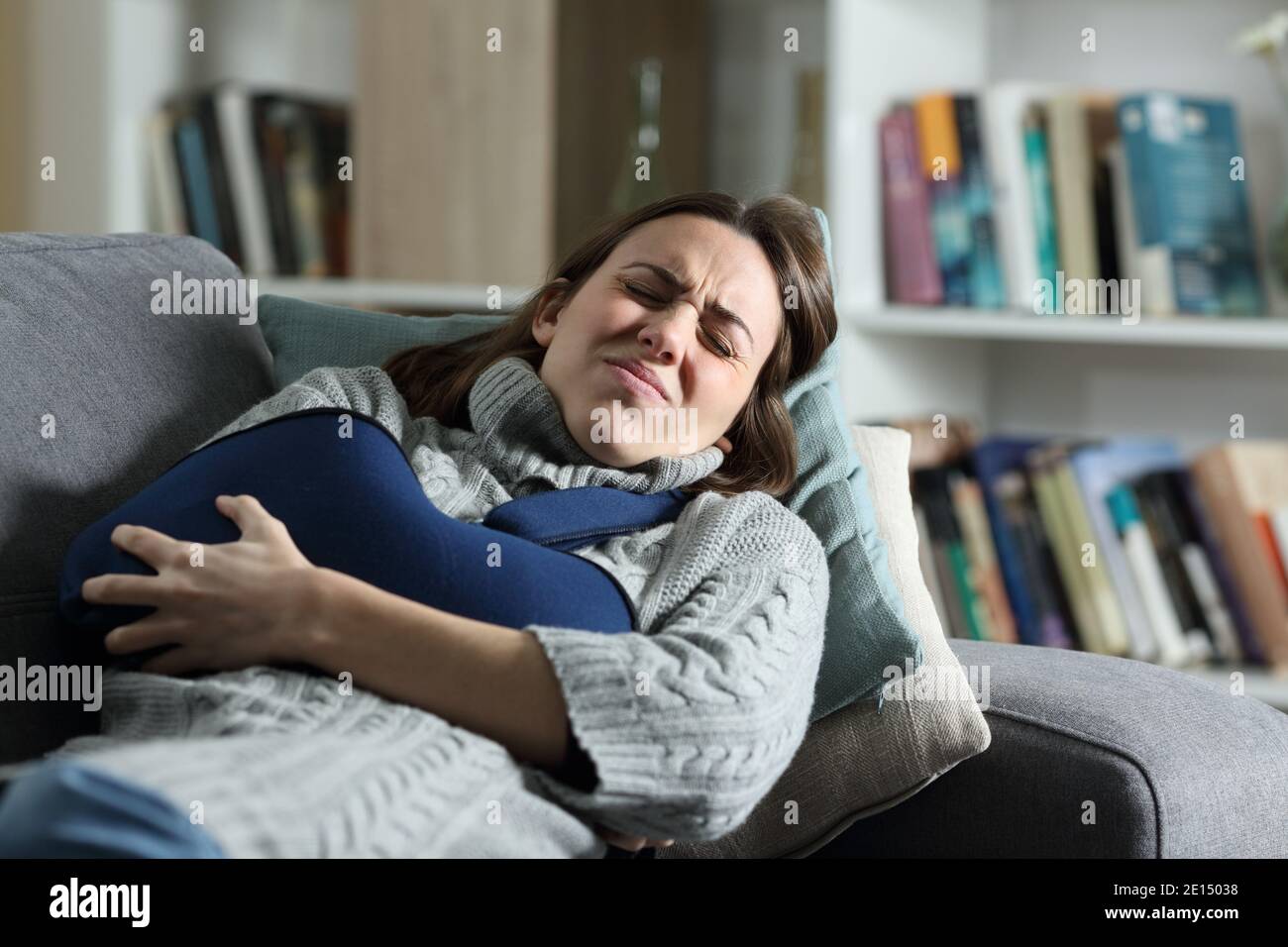 Mujer sufriendo dolor con brazo roto en un cabestrillo en un sofá en casa Foto de stock
