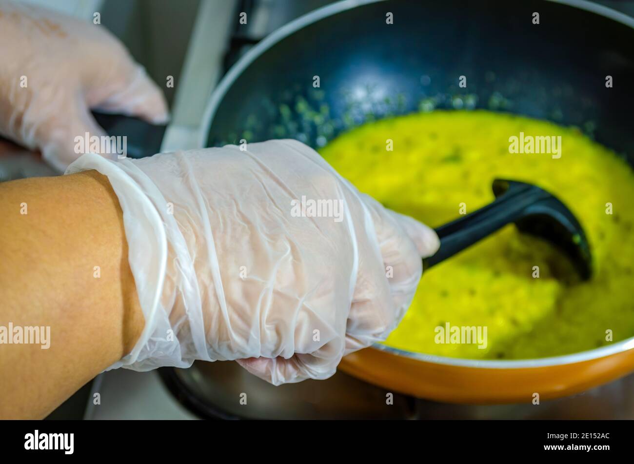 Preparación de un Dal Fry de estilo indio usando guantes en casa - un efecto del virus de la Corona Foto de stock