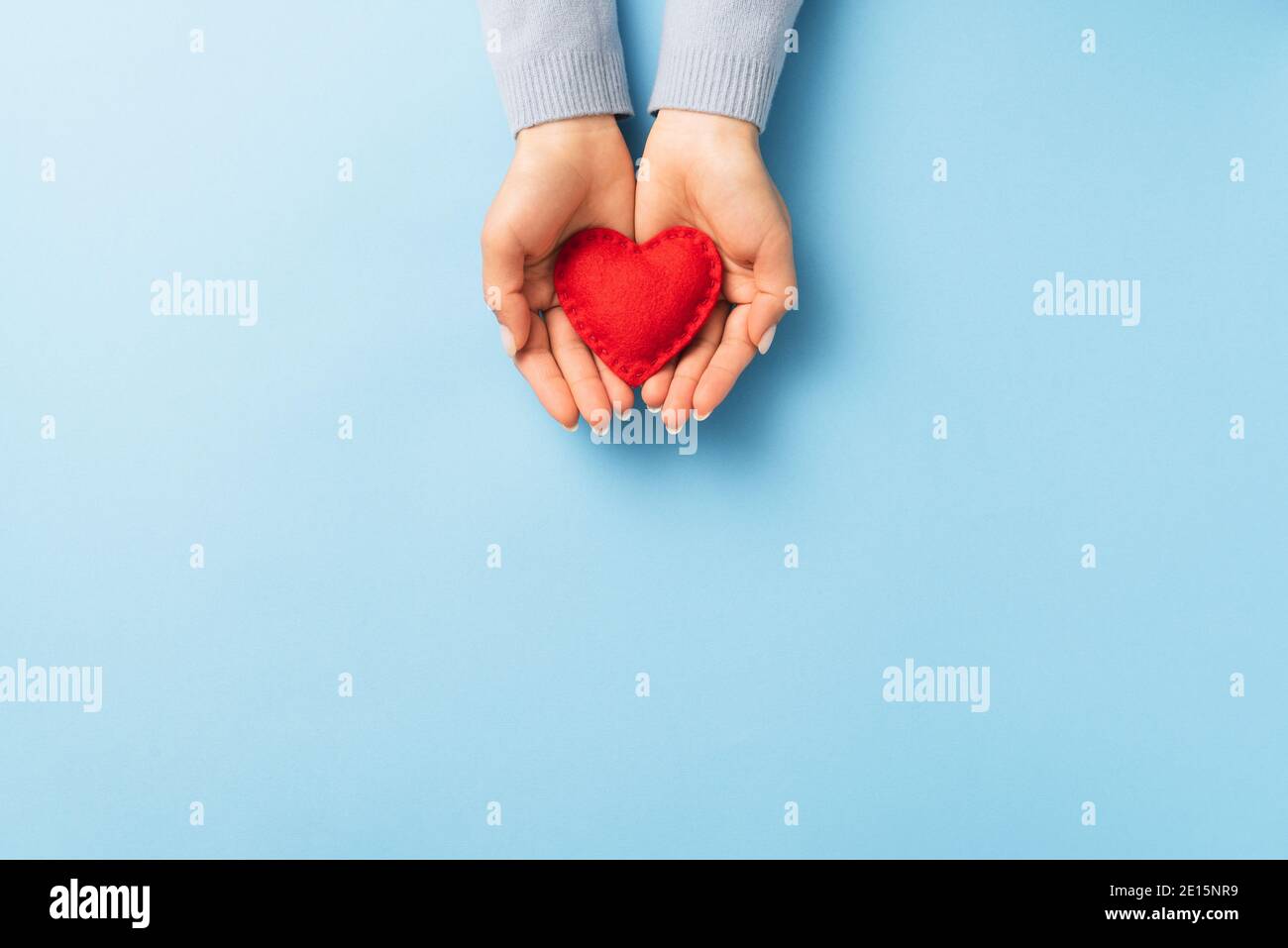 San Valentín con un corazón rojo en un puñado de una mujer sobre un fondo azul con espacio de copia Foto de stock
