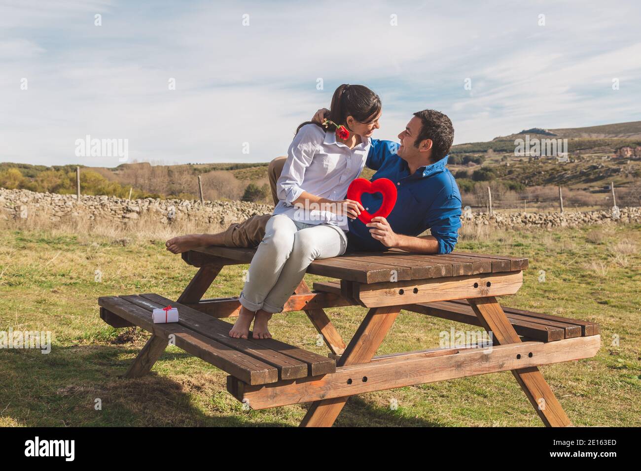 Pareja joven abrazando, besando y disfrutando pasando tiempo juntos celebrando el día de San Valentín en el campo. Me encanta san valentín y R. Foto de stock