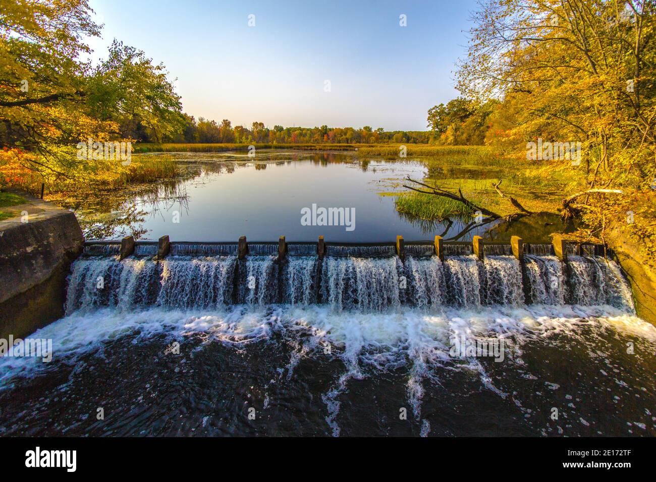 Presa en el río crea un hermoso humedal natural con árboles reflejados en el embalse. Foto de stock