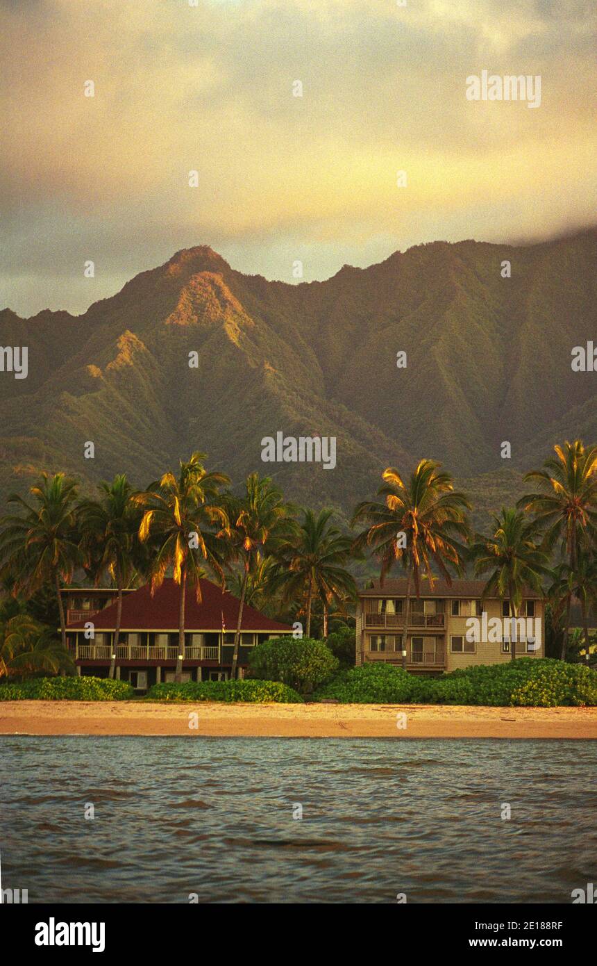 Casas de alquiler de vacaciones frente a la playa con Mt. Ka'ala en el fondo, disparado desde el mar, a la luz de la tarde, en Waialua, en la costa norte de Oahu Foto de stock