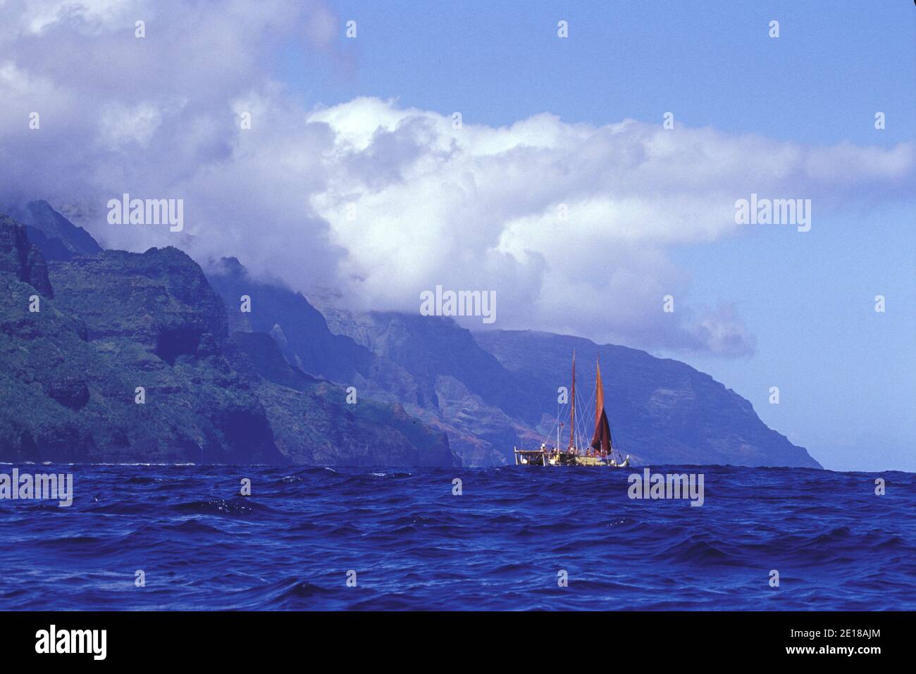 Hokulea, una tradicional canoa hawaiana de doble casco, zarpa de la costa Na Pali para el viaje a las islas hawaianas del noroeste Foto de stock