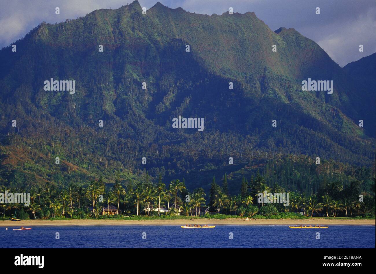 Hanalei Bay's Na Molokama mountain, with Hawaiian canoe paddlers off Hanalei Beach, North Shore, Kauai, Hawaii Foto de stock