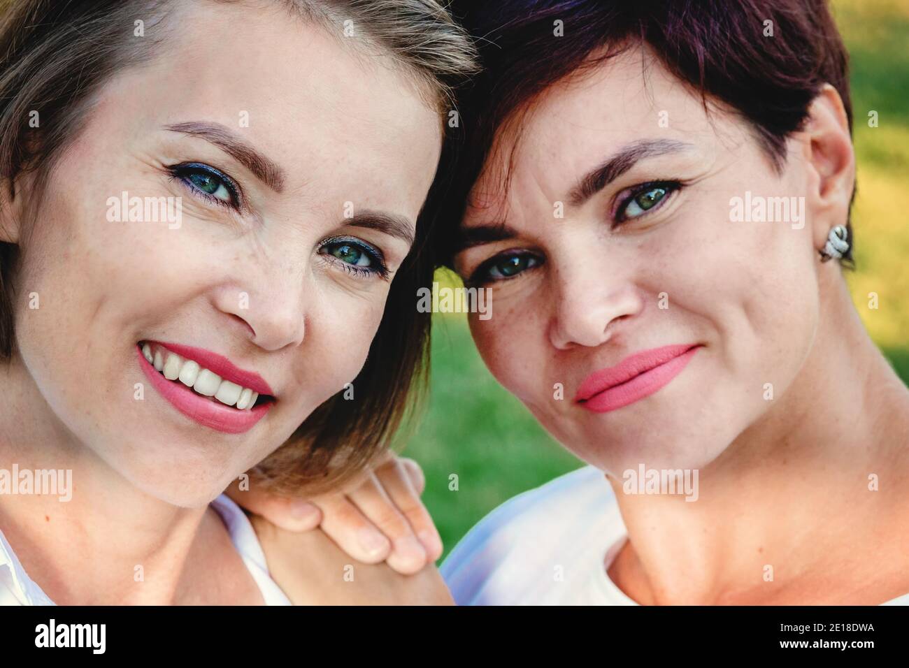 La amistad de las mujeres. Dos hermosas mujeres de apariencia caucásica están sonriendo. Primer plano vertical. Foto de stock