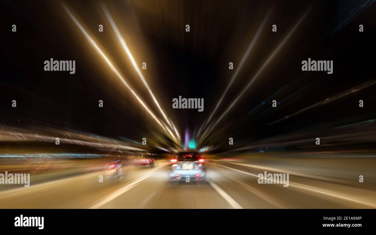 Rayas claras dibujadas debido al movimiento en un gran velocidad en la carretera en coche por la noche Foto de stock