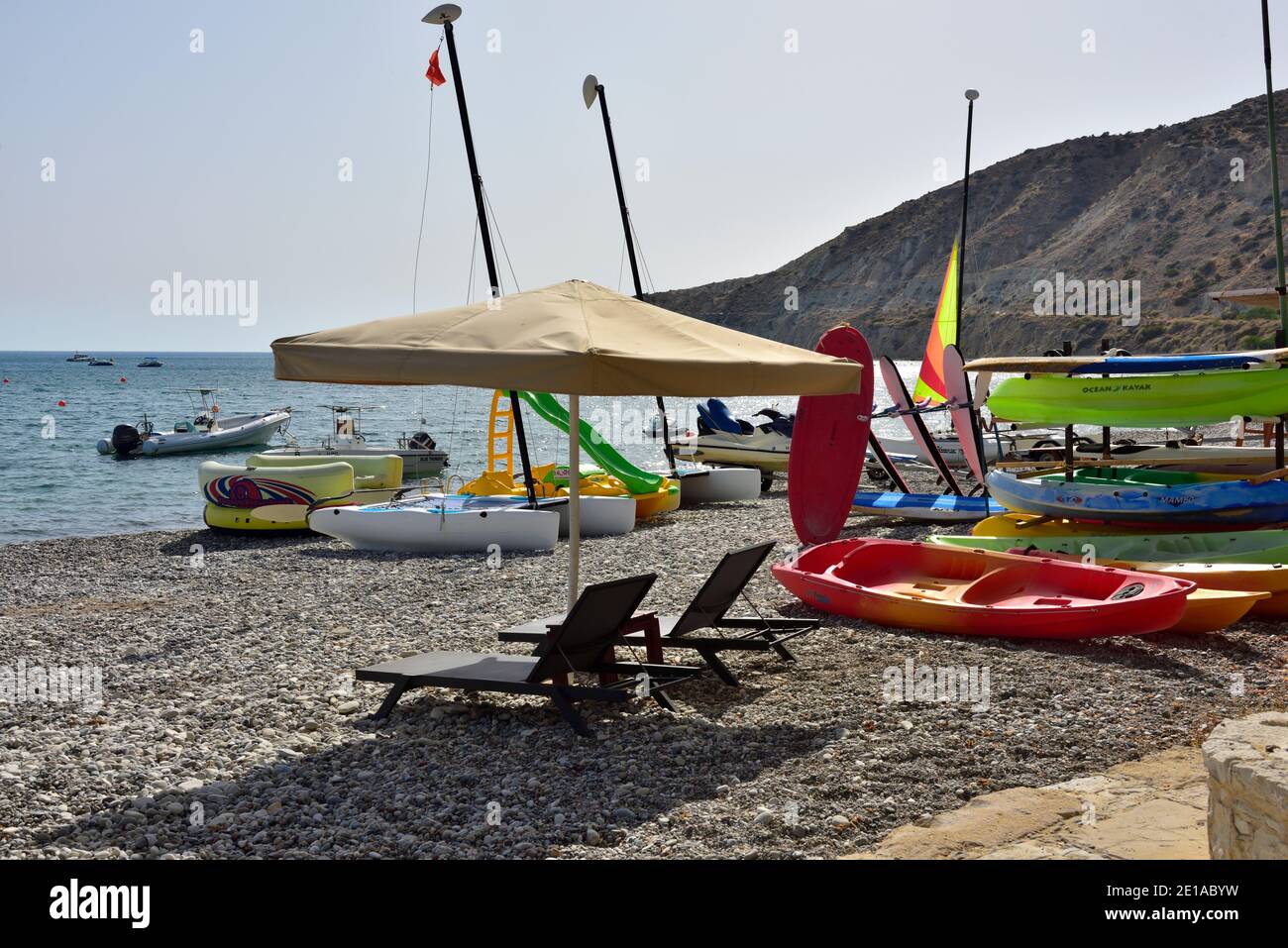 Playa con varios barcos de deportes acuáticos en alquiler (Deportes acuáticos de Columbia (Yiannos & Dia)) en la Bahía de Pissouri, Chipre Foto de stock