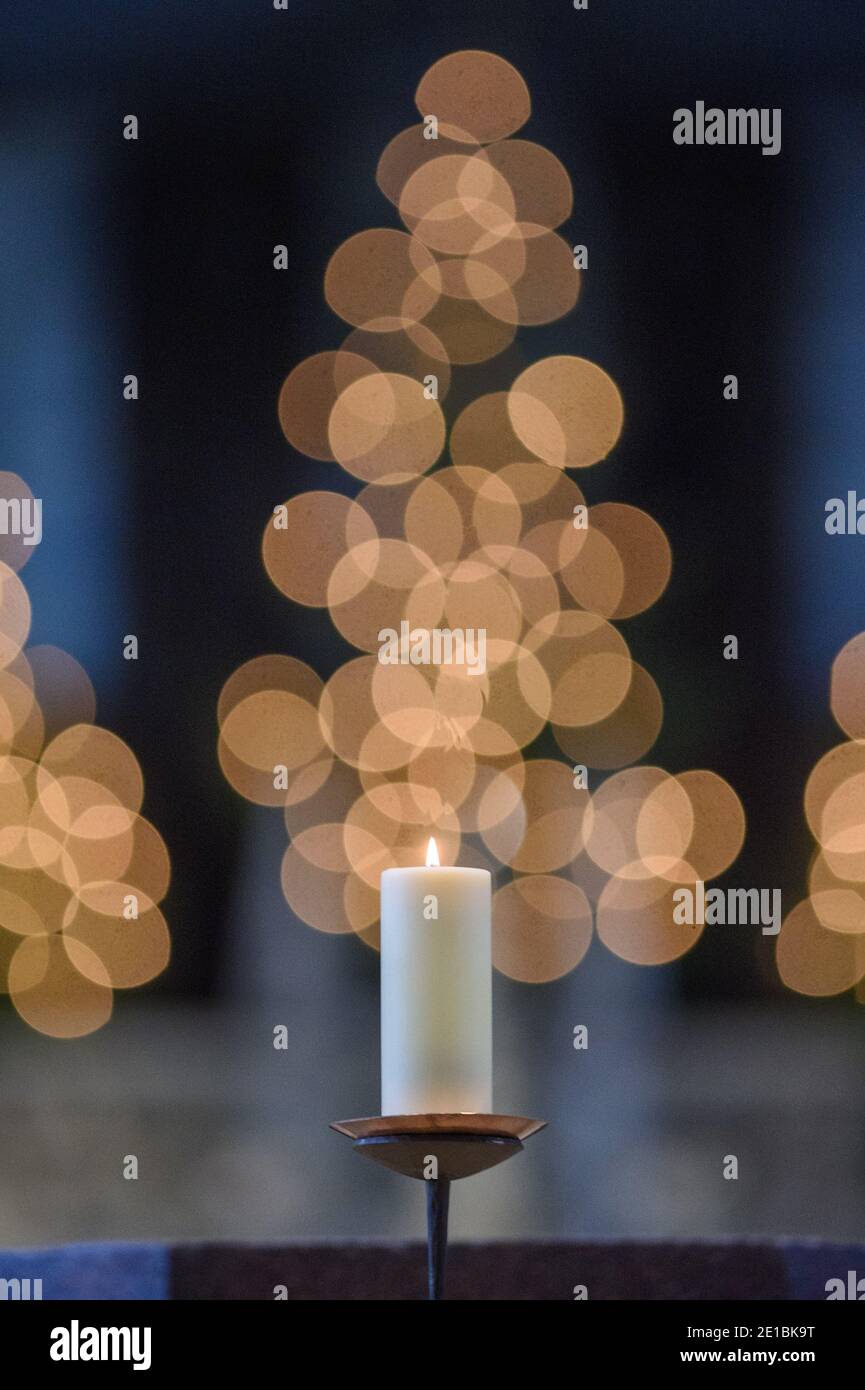 06 de enero de 2021, Sajonia-Anhalt, Magdeburg: Una vela arde en la Catedral de San Mauricio y Catalina en Magdeburg. La congregación de la catedral celebró un servicio allí en Epifanía. En el fondo las velas de un árbol de Navidad están brillando. Debido a la propagación del Coronavirus, solo 100 participantes fueron autorizados para el servicio. Epifanía es una fiesta de la iglesia muy antigua y se celebra el 6 de enero. La palabra, derivada del griego, significa "apariencia" y se refiere a la aparición de Dios en el mundo con el nacimiento de Cristo. En Sajonia-Anhalt, el 6 de enero es una fiesta pública. En el Ch. Católico Foto de stock