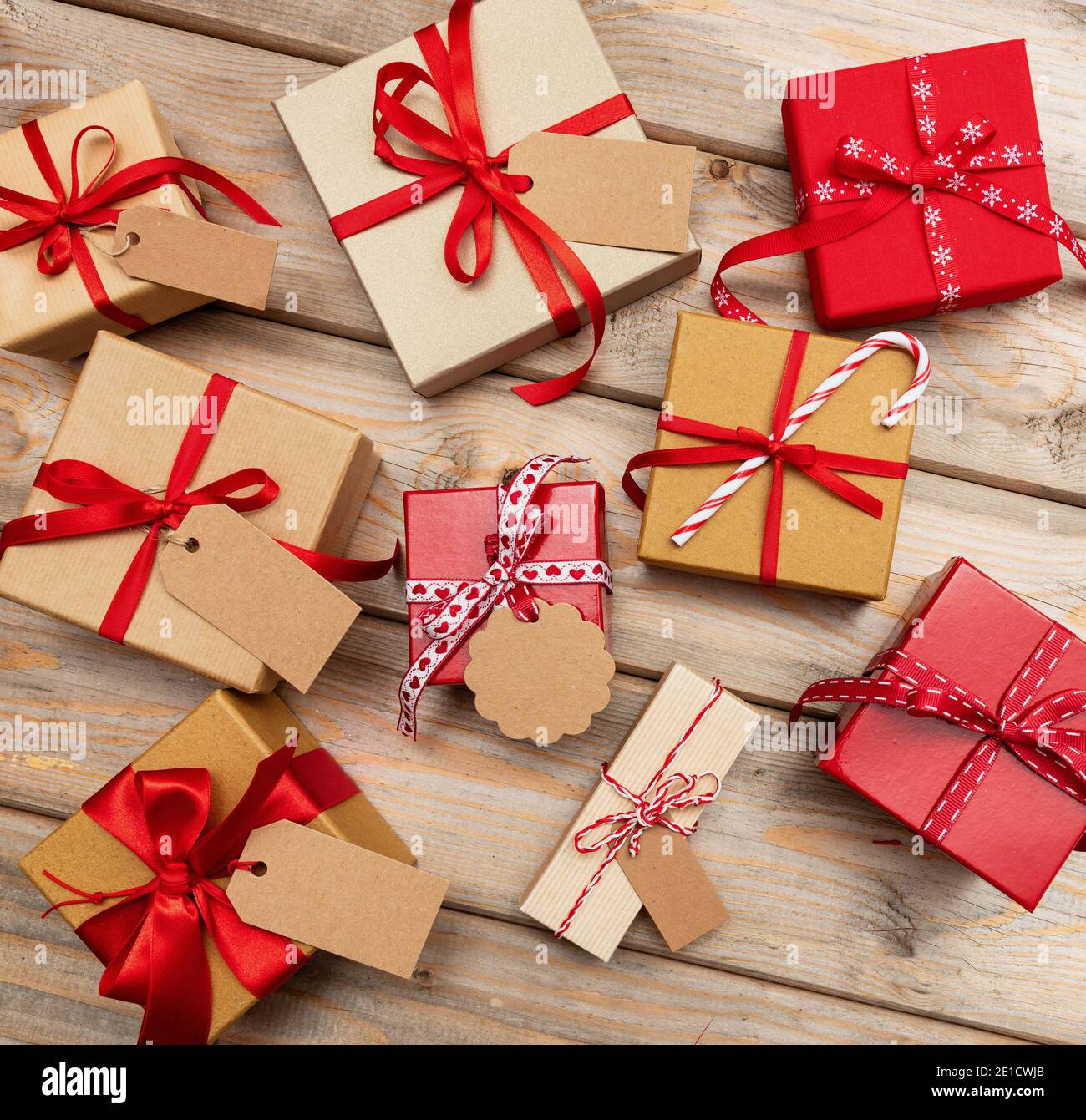 Cajas de regalo de Navidad con etiquetas en blanco sobre fondo de madera.  Lay plano de los paquetes de regalo hechos a mano, papel para envolver  kraft, cinta roja. Ideal para Navidad