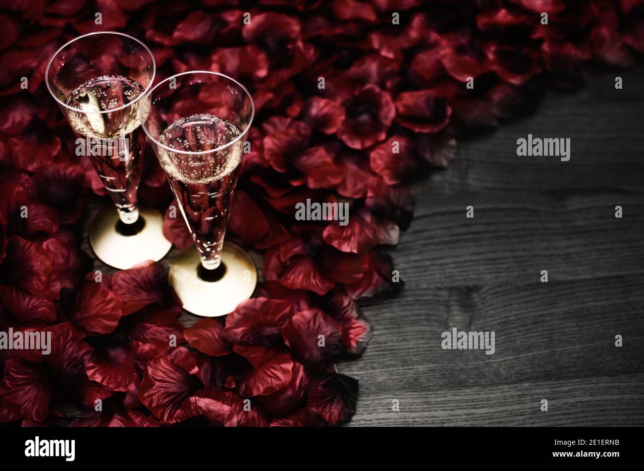 Dos copas de vino espumoso para una tostada romántica sobre pétalos de rosa  roja y mesa de madera como espacio de copia Fotografía de stock - Alamy