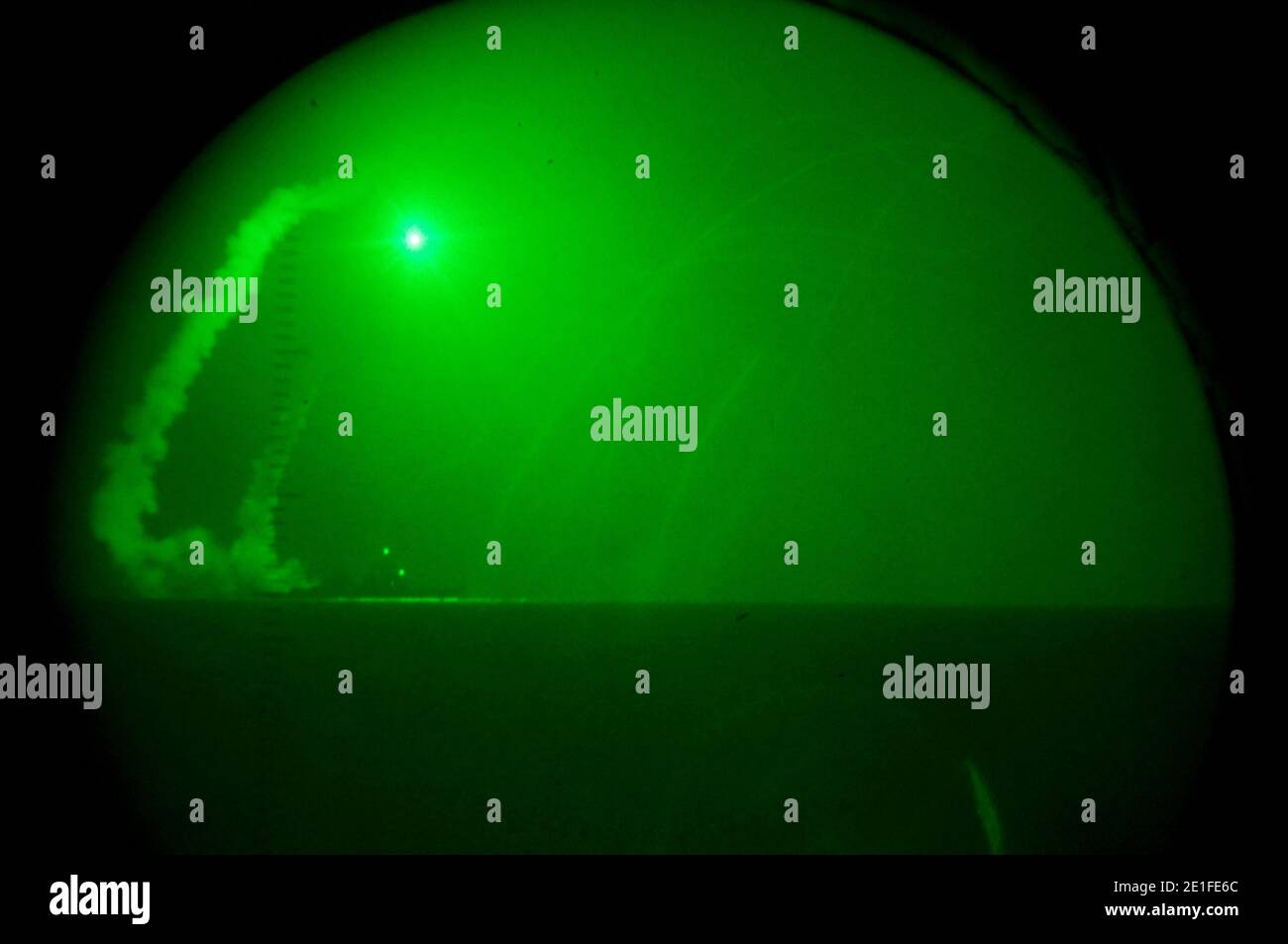 Visto a través de lentes de visión nocturna a bordo del muelle de transporte anfibio USS Ponce (LPD 15), el destructor de misiles guiado USS Barry (DDG 52) dispara misiles de crucero Tomahawk en apoyo de la operación Odyssey Dawn. Este fue uno de aproximadamente 110 misiles de crucero disparados desde buques y submarinos estadounidenses y británicos que apuntaron a unos 20 sitios de radar y antiaéreos a lo largo de la costa mediterránea de Libia. Odisea Dawn es la fuerza de tarea del mando de África de los Estados Unidos establecida para proporcionar el mando operativo y táctico y el control de las fuerzas militares de los Estados Unidos que apoyan la respuesta internacional a las unres Foto de stock