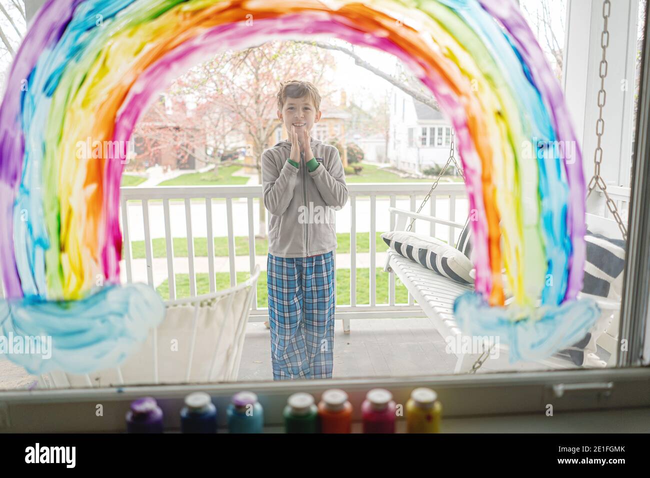 niño sonriente en pijamas bajo el arco iris pintado en la ventana  Fotografía de stock - Alamy