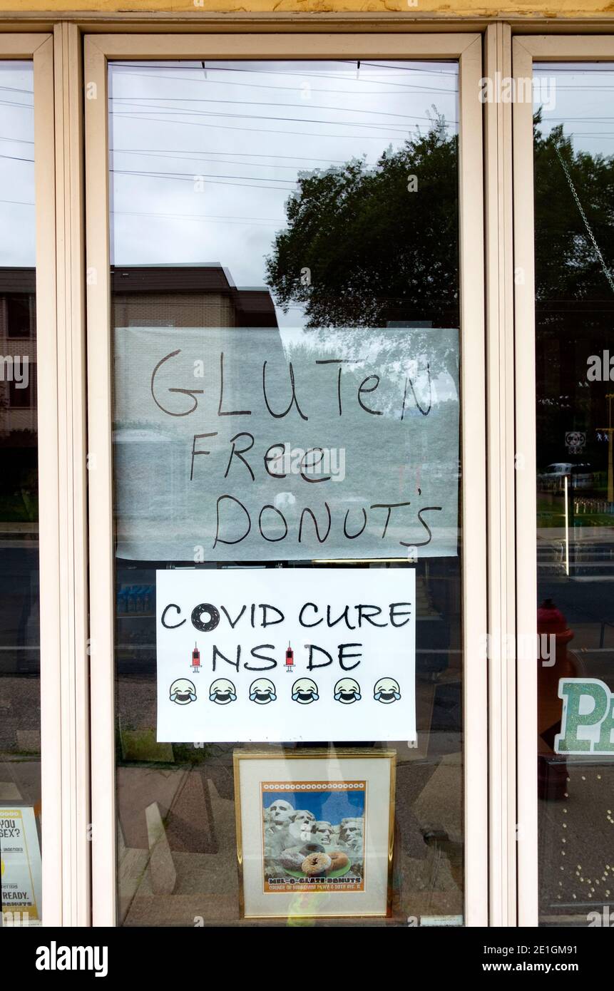 Signo humorístico en la ventana de la panadería Mel-o-Glaze para la cura Covid y donuts sin gluten. Minneapolis Minnesota MN EE.UU Foto de stock
