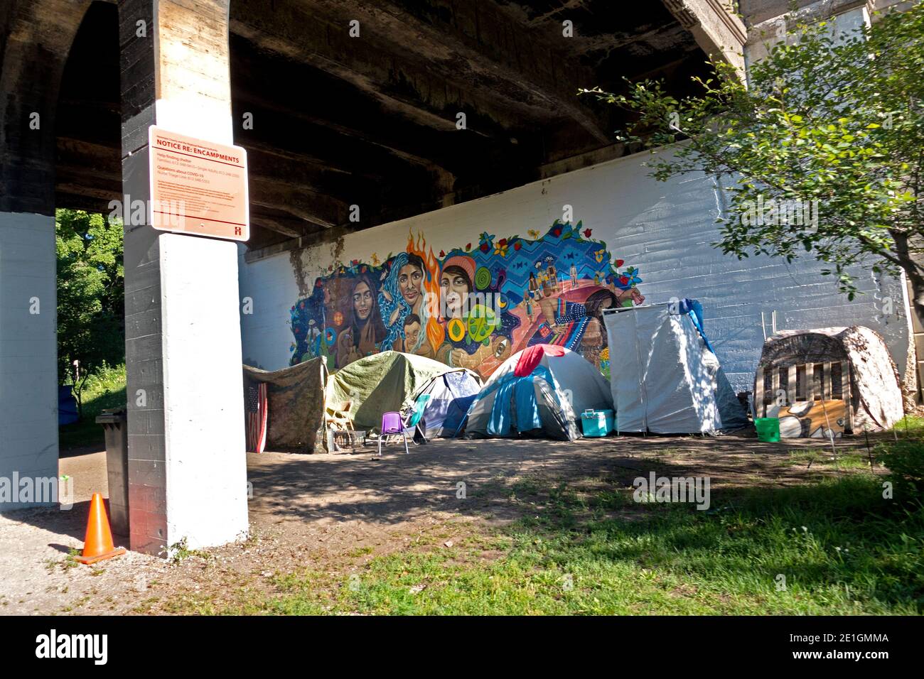 Tiendas de una comunidad sin hogar bajo un puente junto a obras de arte en el sendero para bicicletas y caminatas Midtown Greenway. Minneapolis Minnesota MN EE.UU Foto de stock