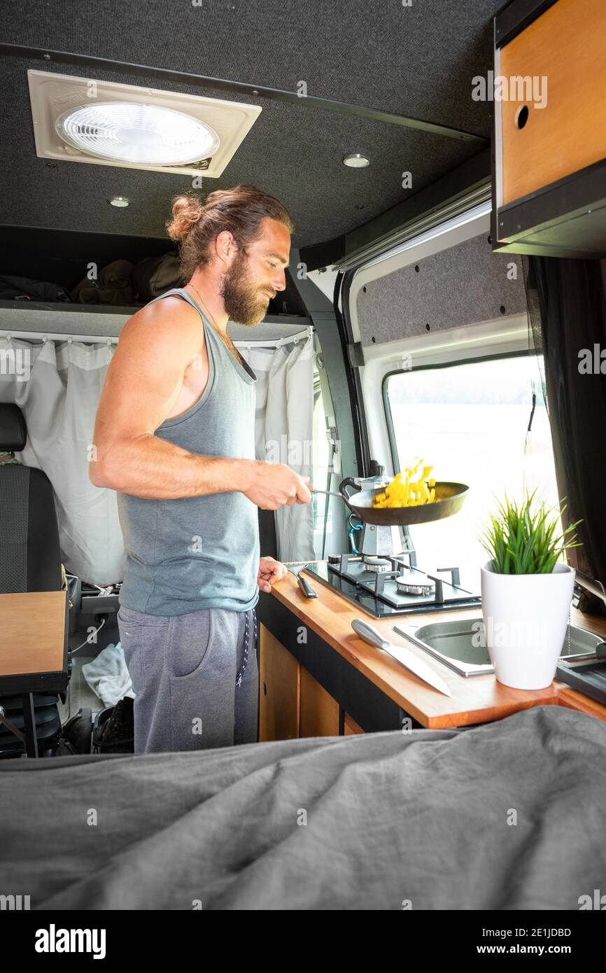 Hombre cocinando comida dentro de su caravana Foto de stock