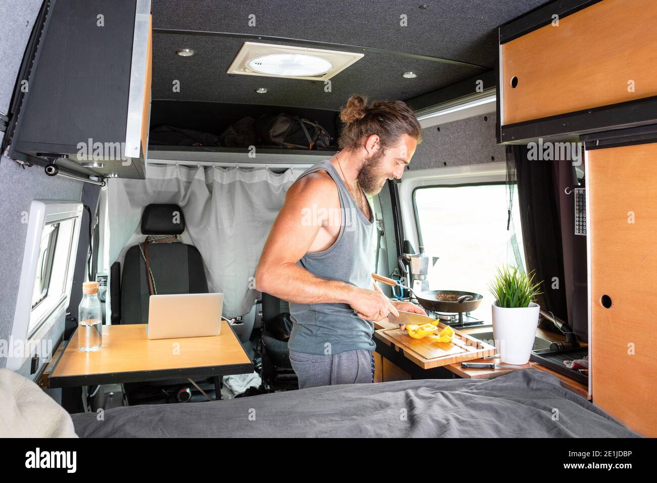 Joven preparando comida dentro de su caravana Foto de stock