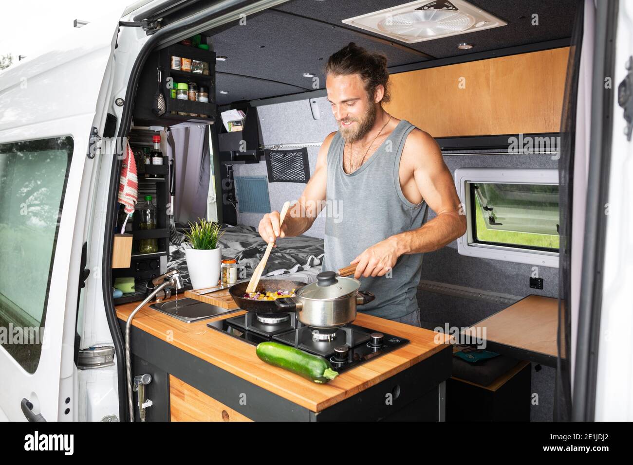Hombre cocinando en una estufa dentro de su camioneta Foto de stock