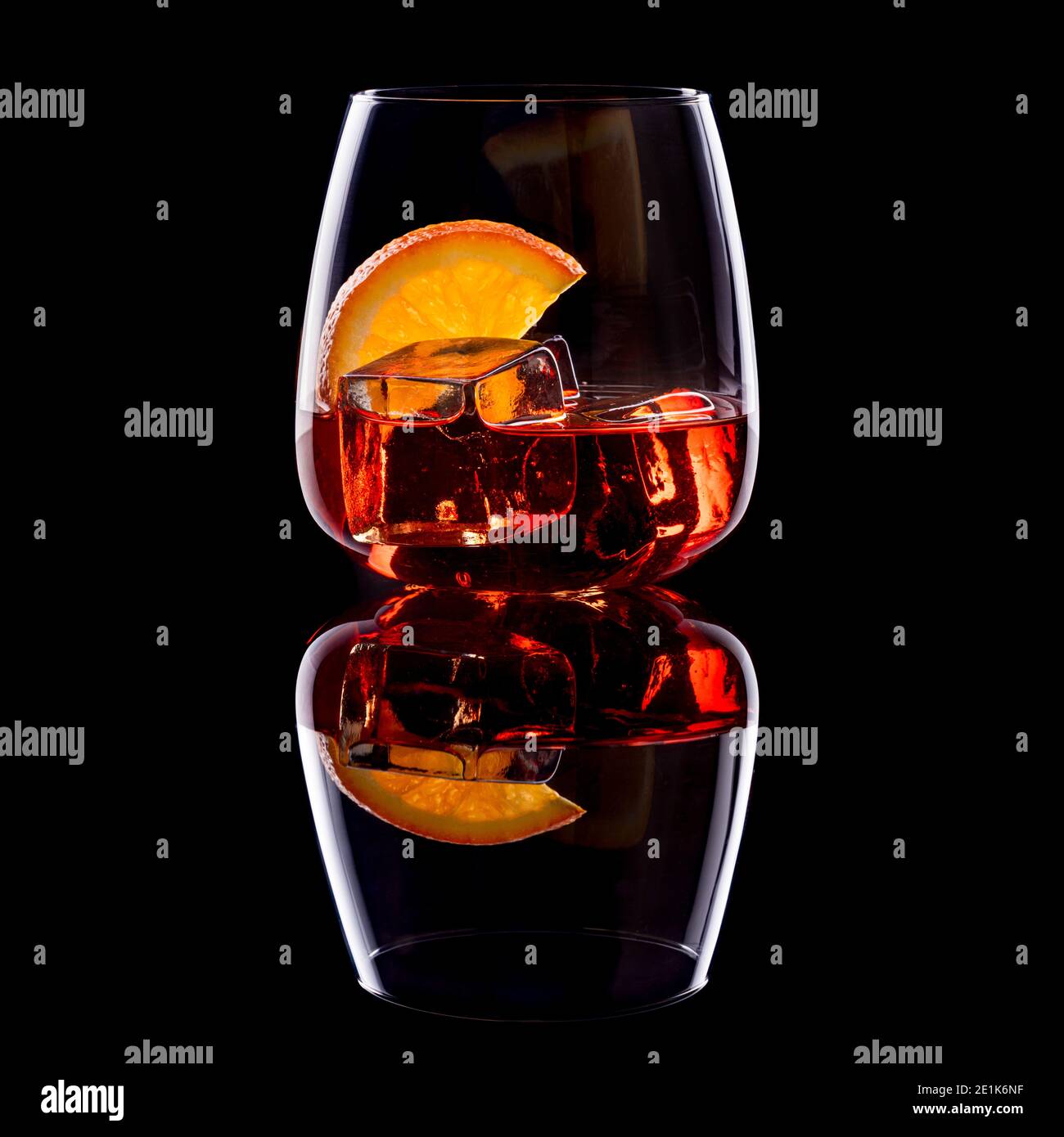 Aperitivo Negroni con cubitos de hielo y una rebanada de naranja en vidrio sobre fondo negro. Foto de stock
