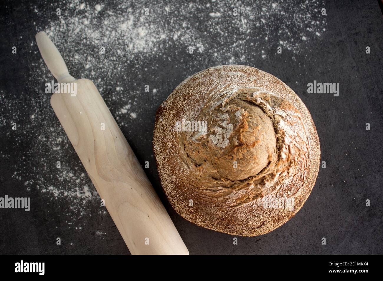 Pan artesano recién horneado sobre una mesa. Fondo gris oscuro con espacio de copia. Receta casera de pan de masa de harina. Foto de stock