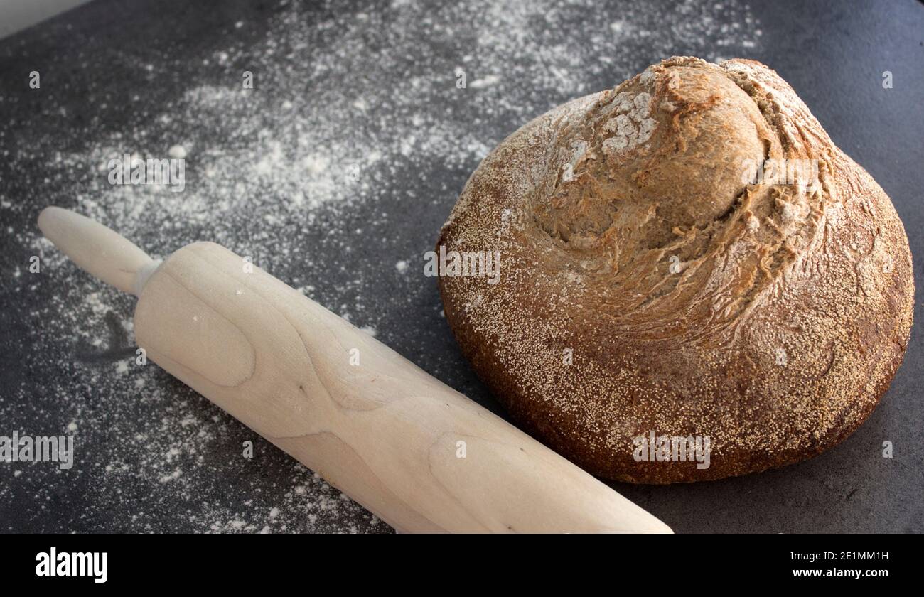 Pan artesano recién horneado sobre una mesa. Fondo gris oscuro con espacio de copia. Receta casera de pan de masa de harina. Foto de stock