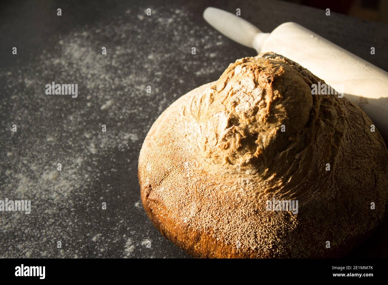 Pan artesano recién horneado sobre una mesa. Fondo gris oscuro con espacio de copia. Receta casera de pan de masa de harina. Foto de stock