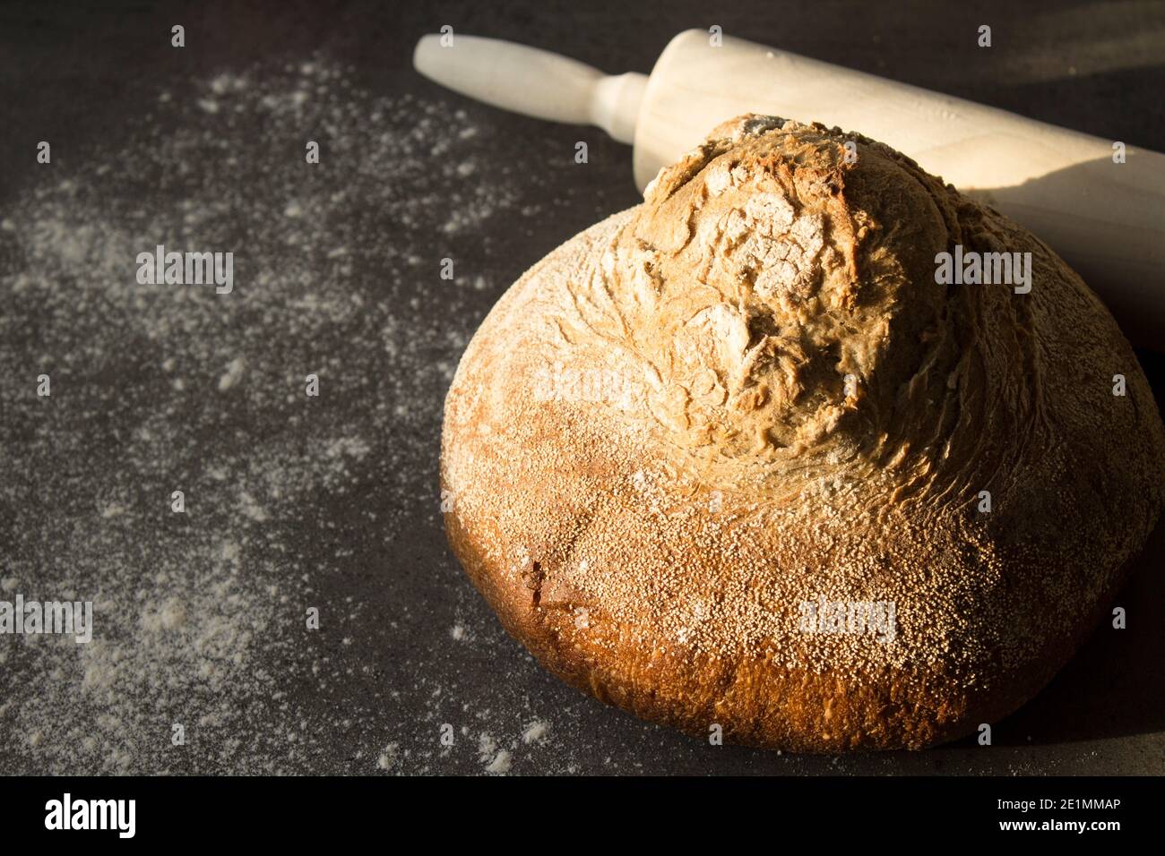 Pan artesano recién horneado sobre una mesa. Fondo gris oscuro con espacio de copia. Receta casera de pan de masa de harina. Foto de stock