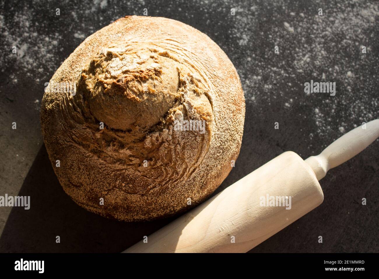 Pan artesano recién horneado sobre una mesa. Fondo gris oscuro con espacio de copia. Receta casera de pan de masa de harina. Foto de stock