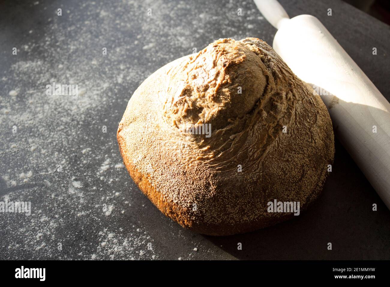 Pan artesano recién horneado sobre una mesa. Fondo gris oscuro con espacio de copia. Receta casera de pan de masa de harina. Foto de stock