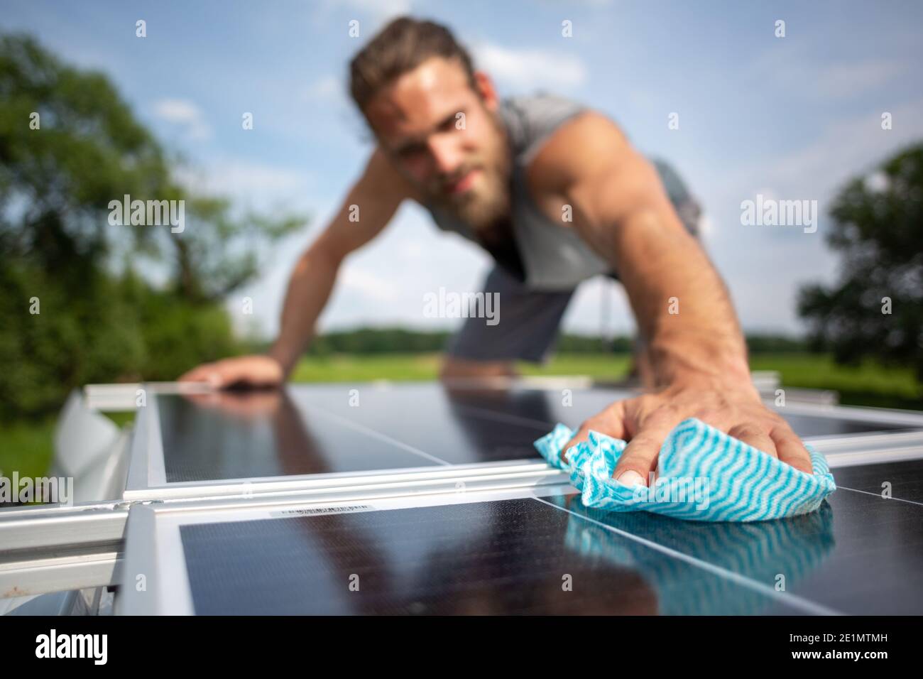 Hombre limpiando un panel solar en el techo de un caravana Foto de stock