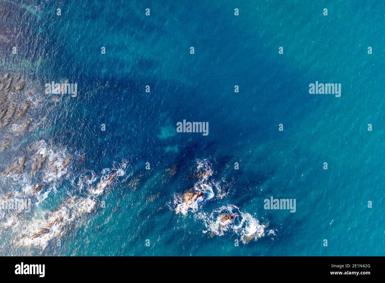 Vista de arriba hacia abajo del mar azul profundo que interactúa con las rocas. Foto de stock