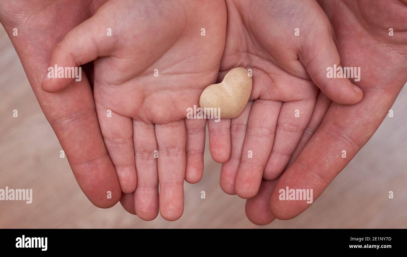 Las manos de papá e hijo sostienen un pequeño corazón de yeso, concepto de  relación familiar Fotografía de stock - Alamy