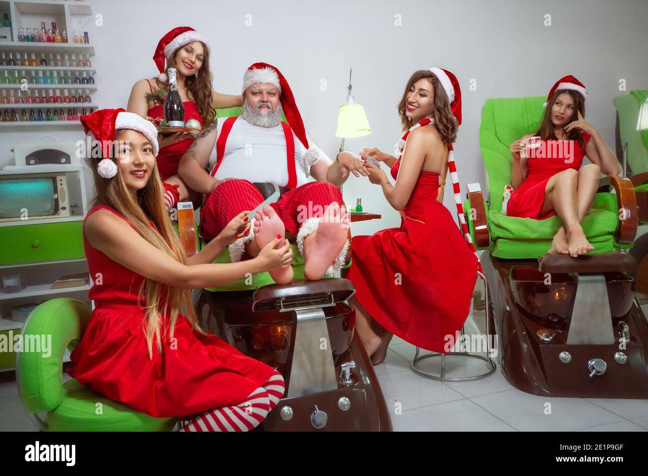 Los ayudantes de Santa Claus hacen manicura y pedicura a Santa Claus en un salón de spa Foto de stock