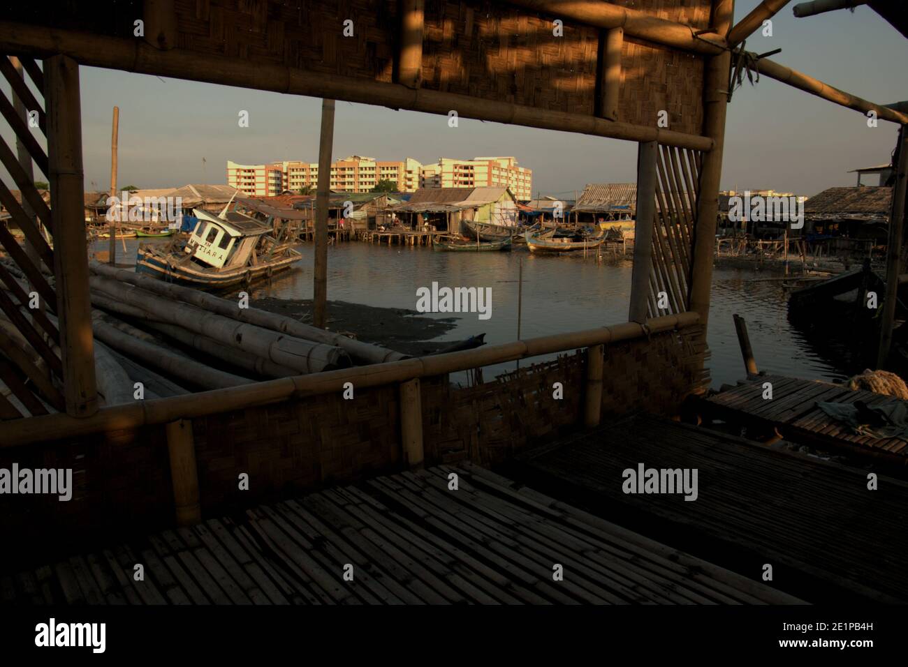 Barcos de pesca en la zona intermareal, aldea de pescadores y edificio plano de nueva construcción visto desde el interior de un restaurante de comida marina abandonado en la aldea de Marunda en la zona costera de Yakarta, Indonesia. Foto de archivo (2008). Foto de stock